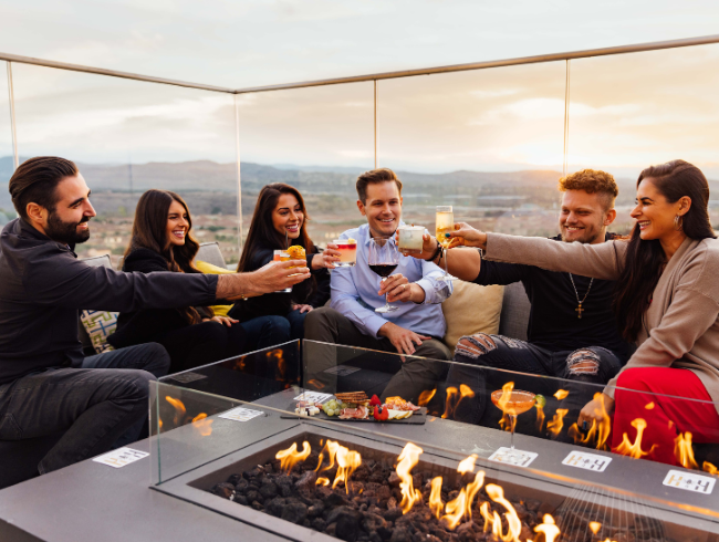 group cheers at a firepit on the hive & honey rooftop